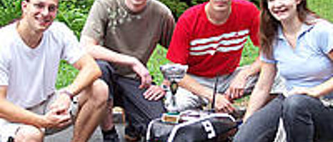 Das Würzburger Team (von links: Manuel Stahl, Daniel Eck, Martin Hess und Doris Aschenbrenner) mit dem Roboterfahrzeug Outdoor Merlin, das den Siegerpokal trägt. Foto: Institut für Informatik