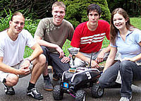 Das Würzburger Team (von links: Manuel Stahl, Daniel Eck, Martin Hess und Doris Aschenbrenner) mit dem Roboterfahrzeug Outdoor Merlin, das den Siegerpokal trägt. Foto: Institut für Informatik